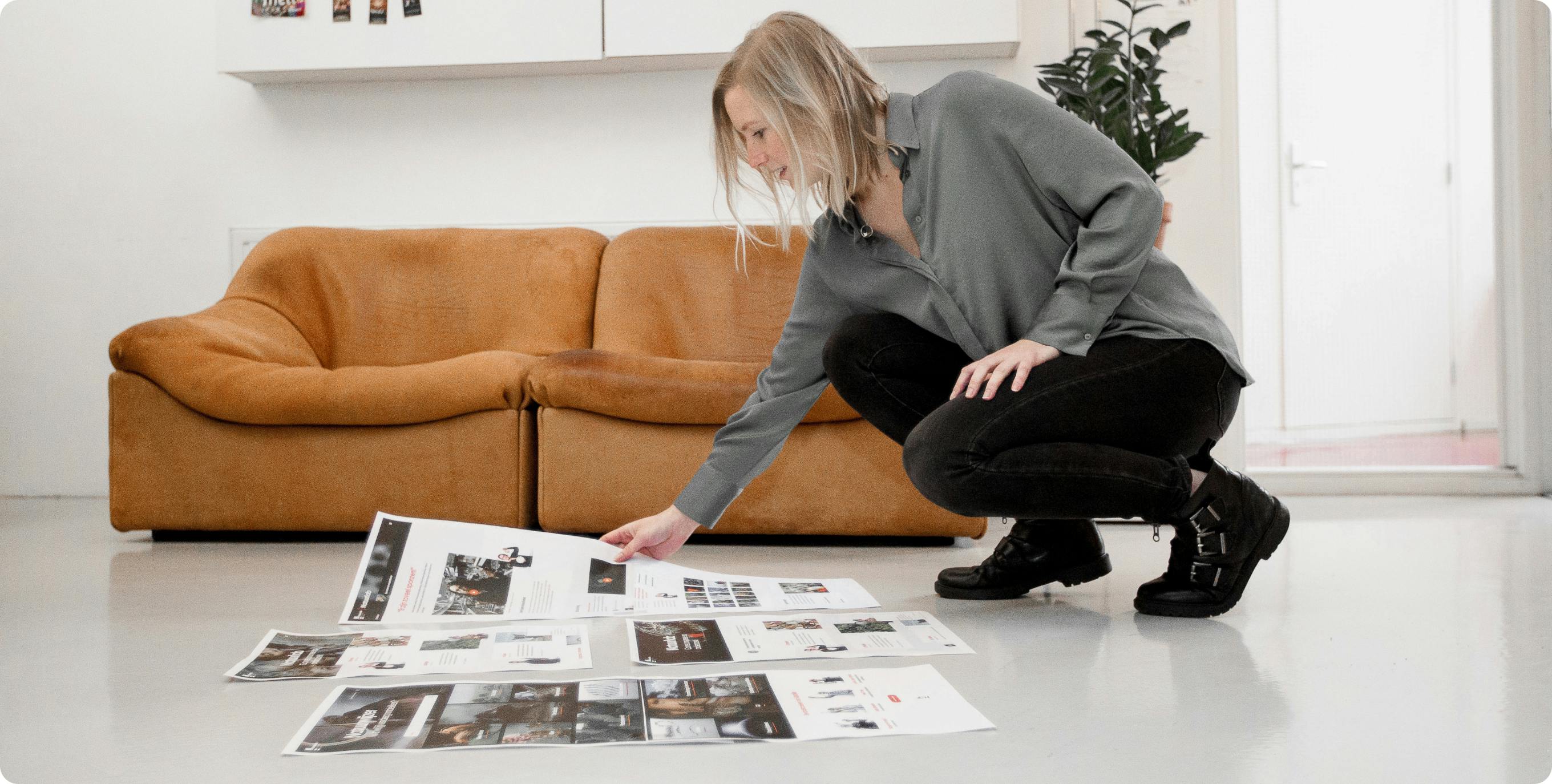 Een ontwerper zit geknield op de grond en bekijkt een aantal prints van een ontwerp.